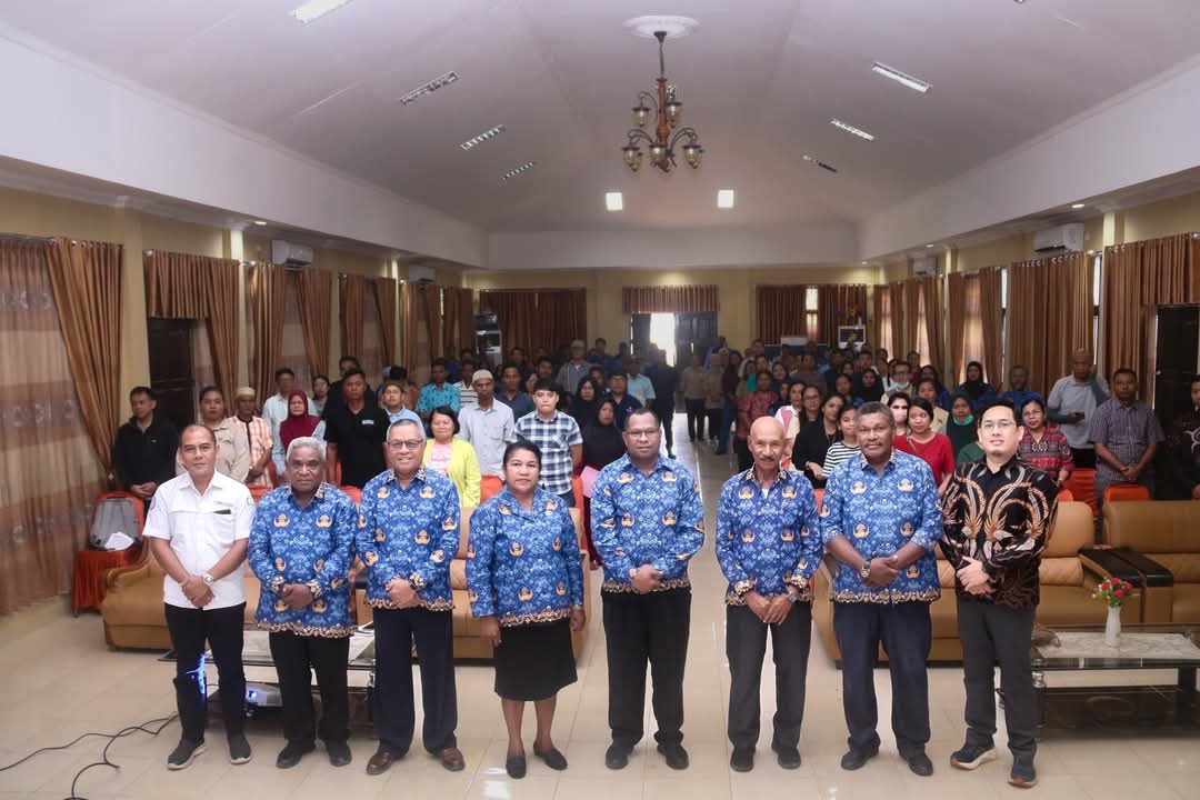 Para pejabat Pemerintah Kabupaten Raja Ampat berfoto bersama peserta sosialisasi usai peluncuran aplikasi SIMPATDA.Barisan depan terdiri dari pejabat BP2RD dan tamu undangan, sementara peserta sosialisasi duduk dan berdiri di belakang mereka dalam aula dengan pencahayaan terang dan tirai coklat.