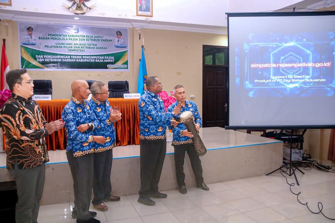 sebagai tanda peresmian, didampingi Kepala BP2RD dan Direktur PT Digi Sistem Solusindo. Acara berlangsung di Aula Dinas Pendidikan dan Kebudayaan, dengan layar proyektor menampilkan laman resmi aplikasi.