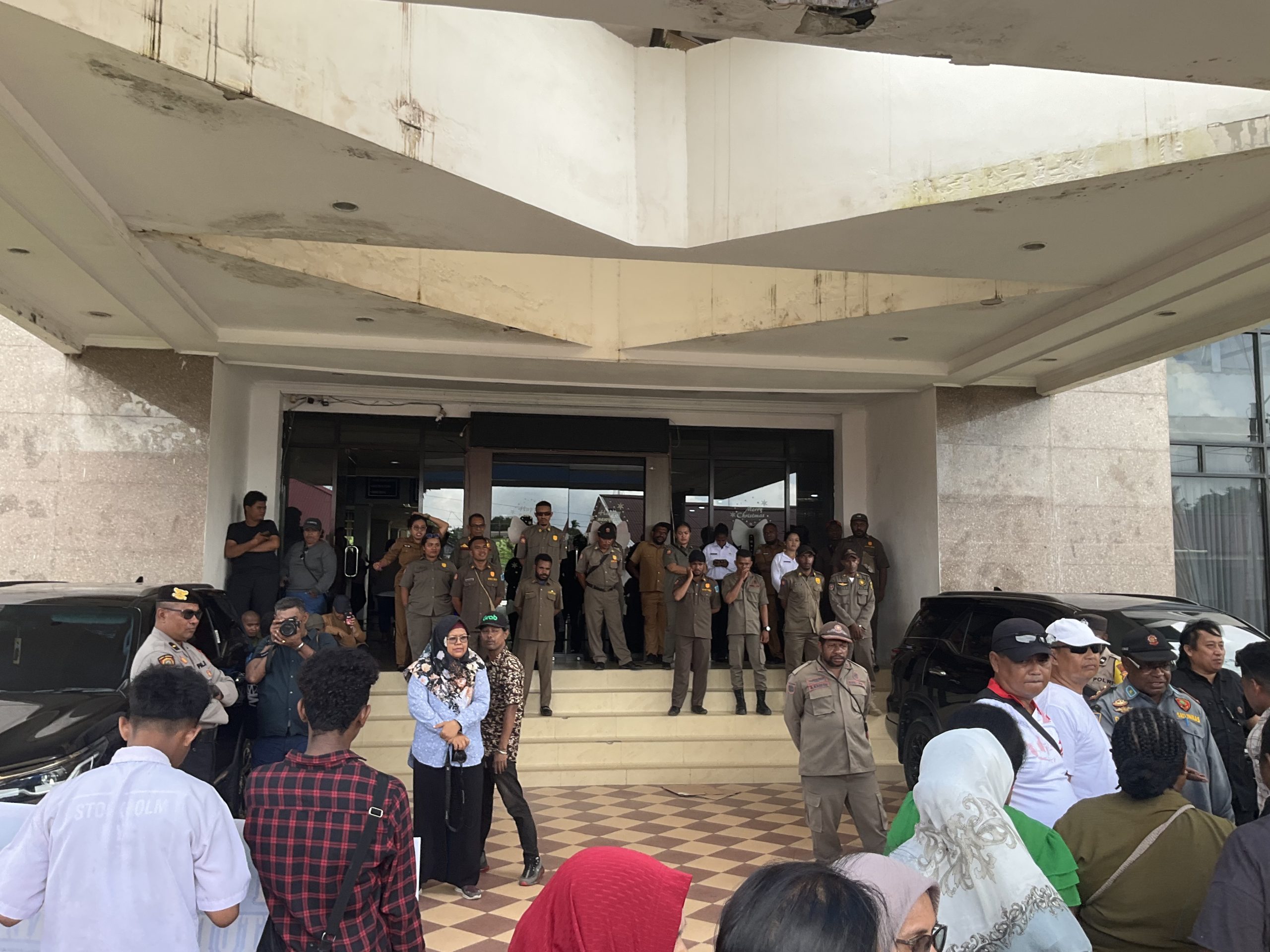 Petugas Satpol PP dan aparat keamanan berjaga di depan pintu masuk kantor Dinas Pendidikan Provinsi Papua Barat Daya di Kota Sorong saat berlangsungnya aksi protes dari orang tua siswa dan mahasiswa terkait kebijakan PPDB SMA Negeri 3.